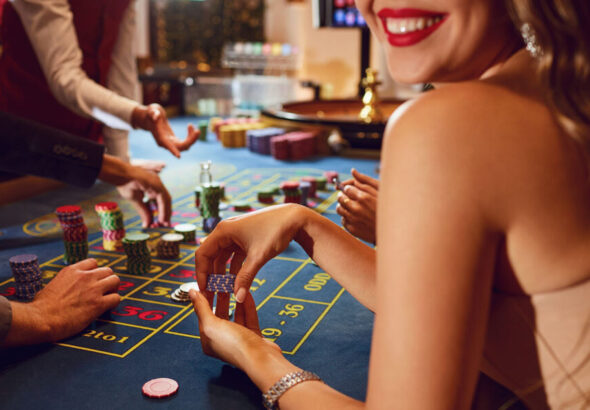 Chips in the hands of a female roulette player in casino background.